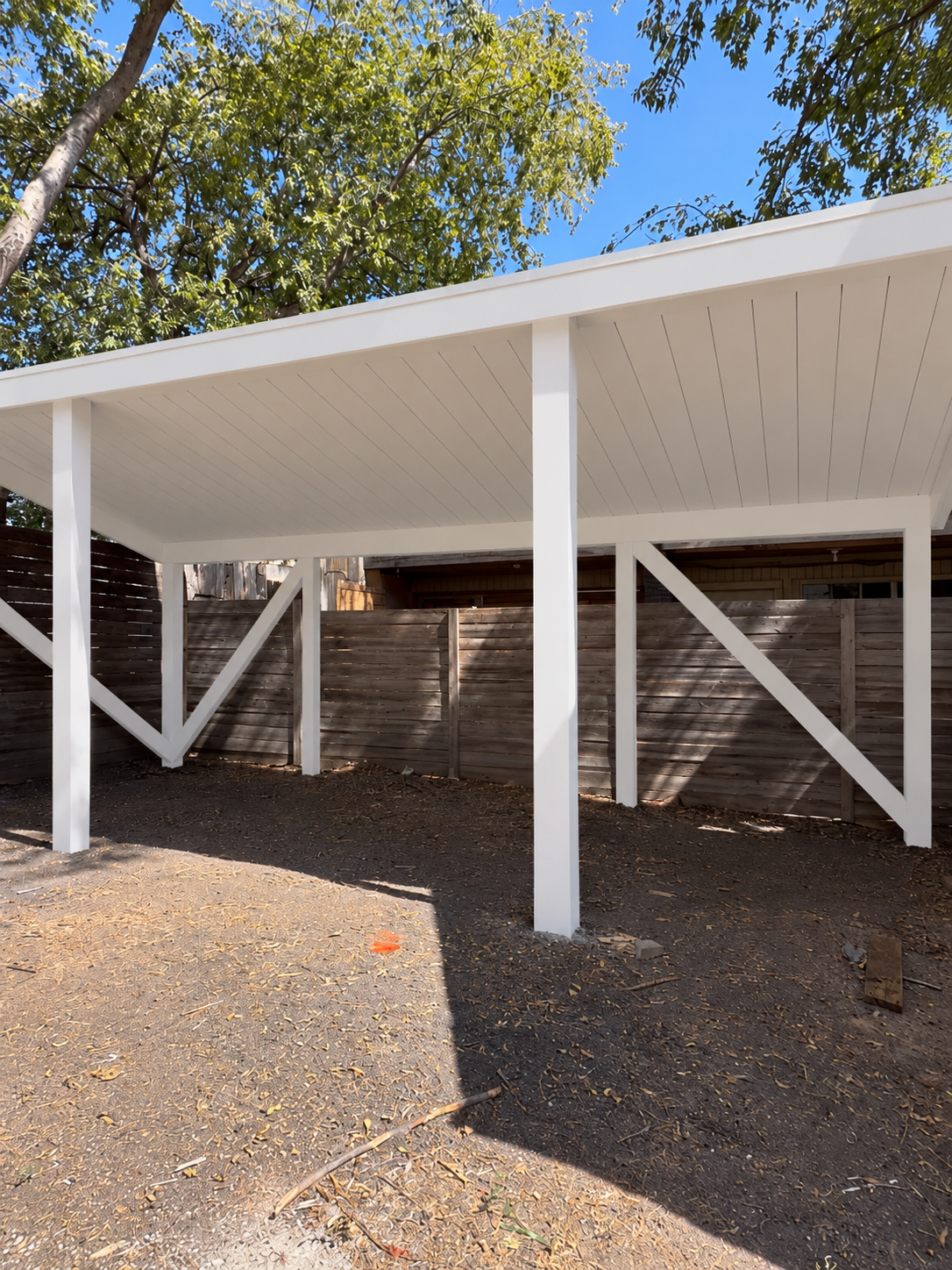 Jeff’s finished white pergola with a shiplap ceiling and braced posts in front of a horizontal wood privacy fence