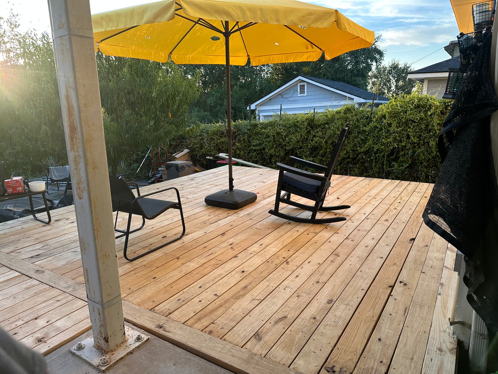 Samual’s new 20 by 30 pine deck with a yellow patio umbrella and a rocking chair